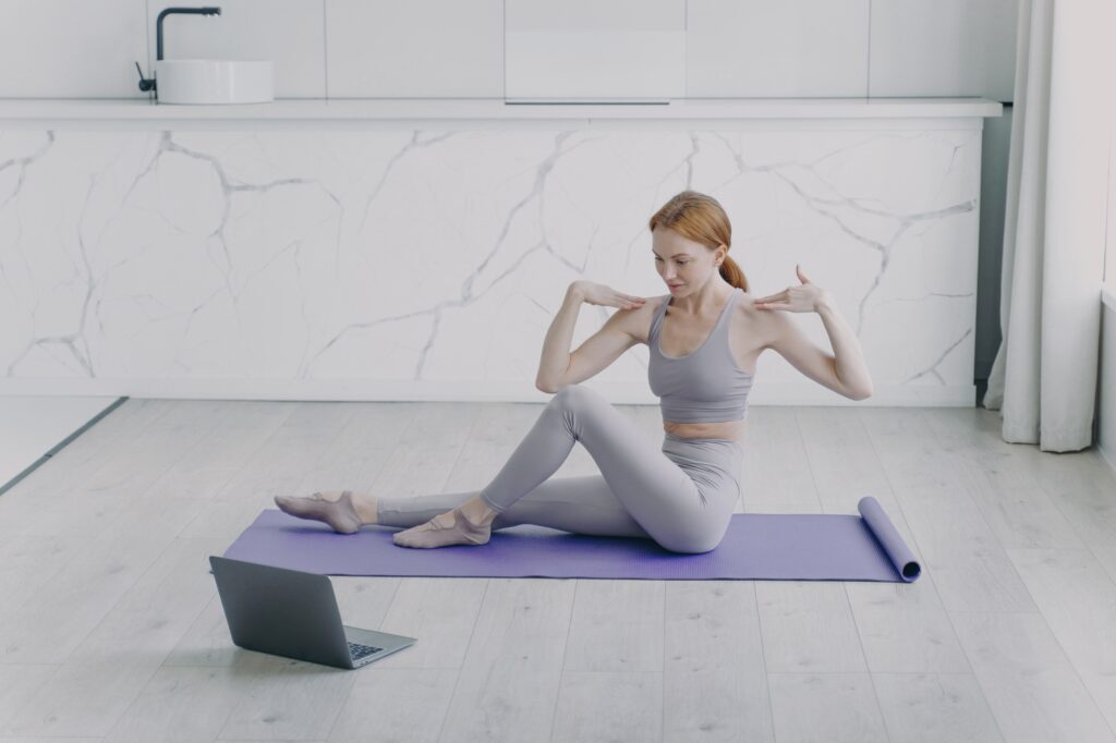 Sport teacher has online lesson and stretching on mat. Physical therapy and yoga at home.